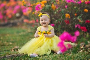Bộ ảnh em bé mặc váy vàng bên hàng hoa giấy